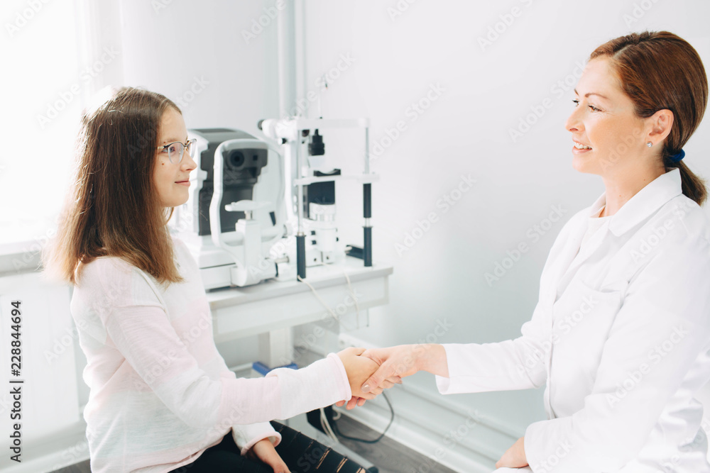 Fototapeta premium Handshake with patient, teenage girl's patient at optometrist office. Doctor, consultation and reception of children
