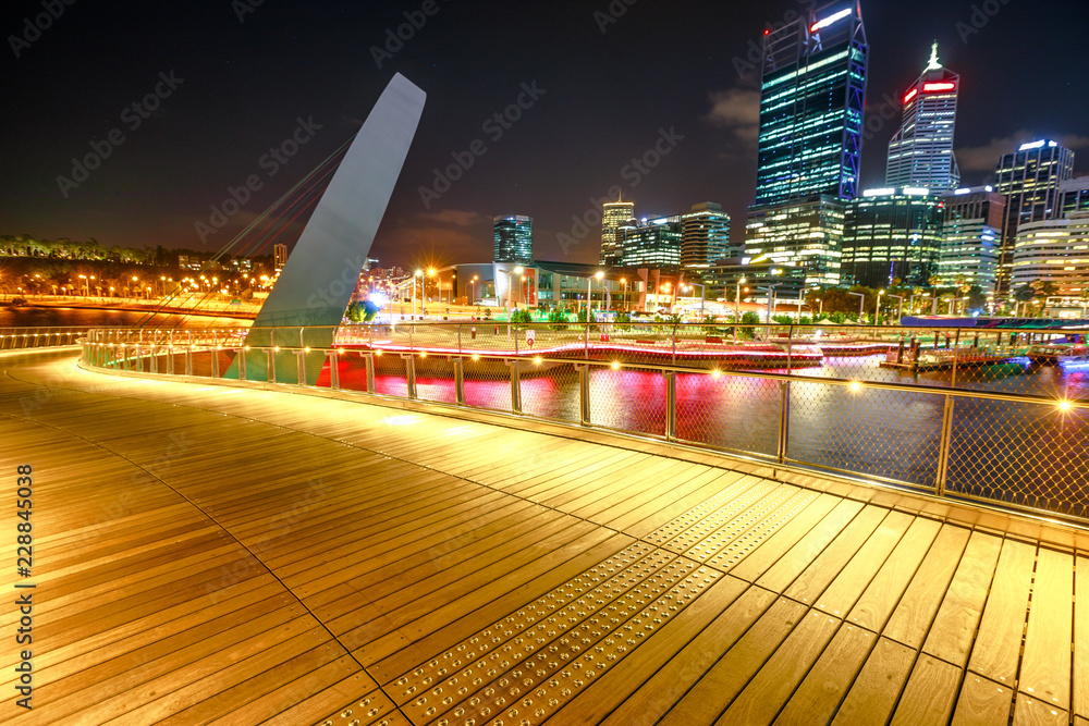 Wooden walkway of Elizabeth Quay pedestrian bridge illuminated by night