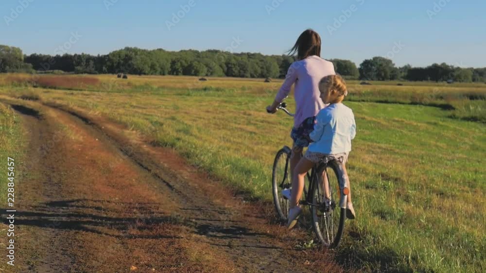 Mother with daughter on bicycles in a meadow. Family on bicycles in nature. The concept of the family. Mother with daughter on bicycles in a meadow. Family on bicycles in nature. The concept of the family.