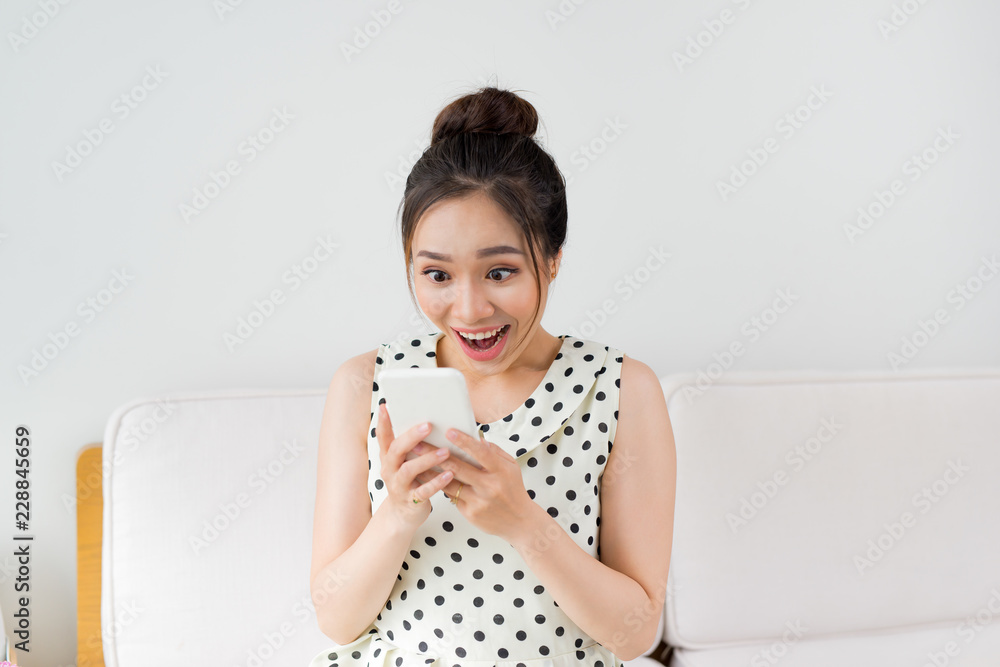 Young asian woman sitting on couch at home and using smartphone. Young asian woman sitting on couch at home and using smartphone.