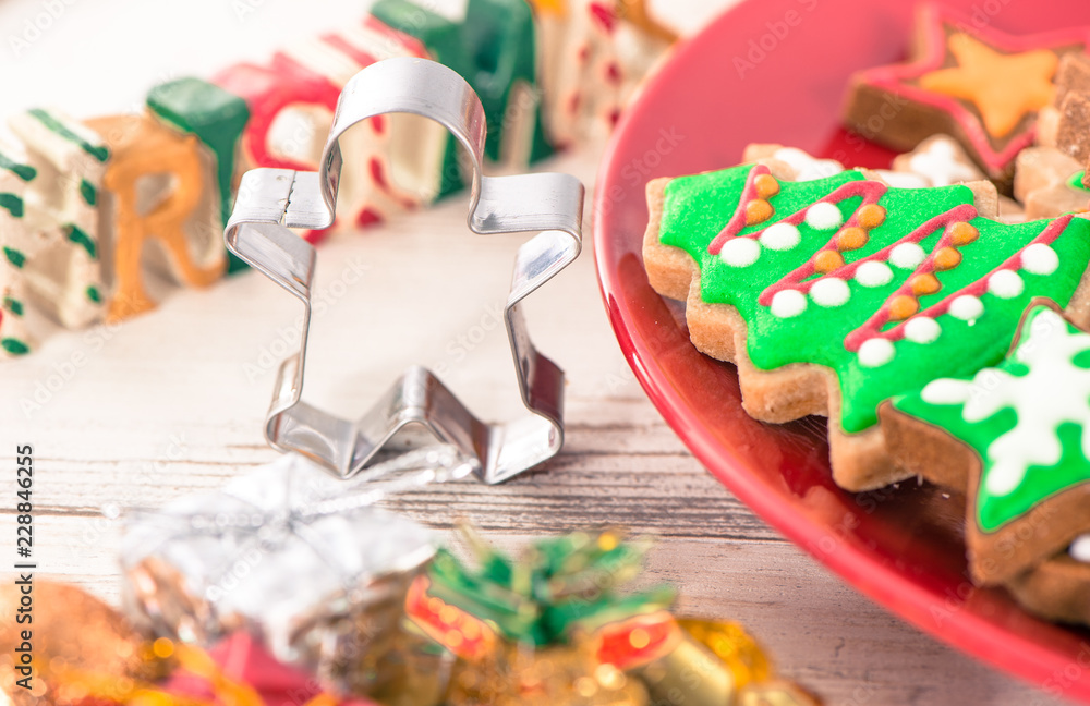 Tasty and cute baked Christmas cookies (gingerbread) with beautiful xmas decoration in red plate on light wooden table background, close up, copy space (text space) Tasty and cute baked Christmas cookies (gingerbread) with beautiful xmas decoration in red plate on light wooden table background, close up, copy space (text space)