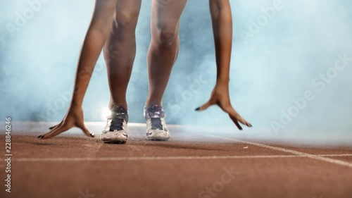 Asian Athlete ready to start. Young female runner preparing for blasting off in mist on sports track of stadium, training before competition photo