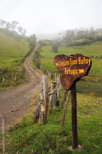 Dirt road surounded by fields, road sign to Refuge in case of volcano eruption. Ecuador. photo