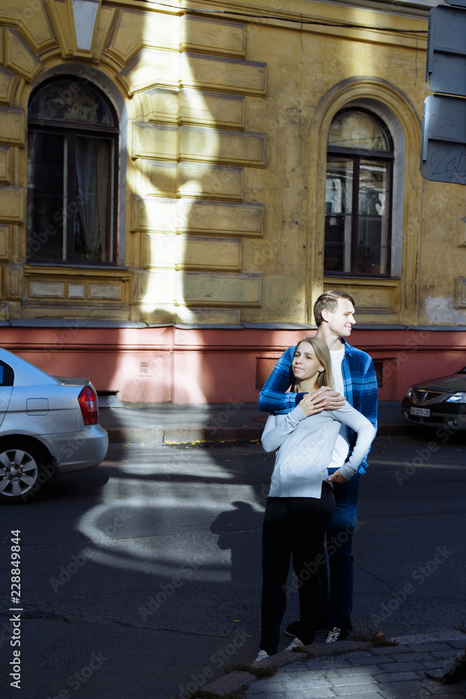 Portrait of a happy couple hugging in the street, in the city.standing in better from the sun, hard light. date.the sun shines on the faces, the rays of the sun between a man and a woman, a kiss Portrait of a happy couple hugging in the street, in the city.standing in better from the sun, hard light. date.the sun shines on the faces, the rays of the sun between a man and a woman, a kiss