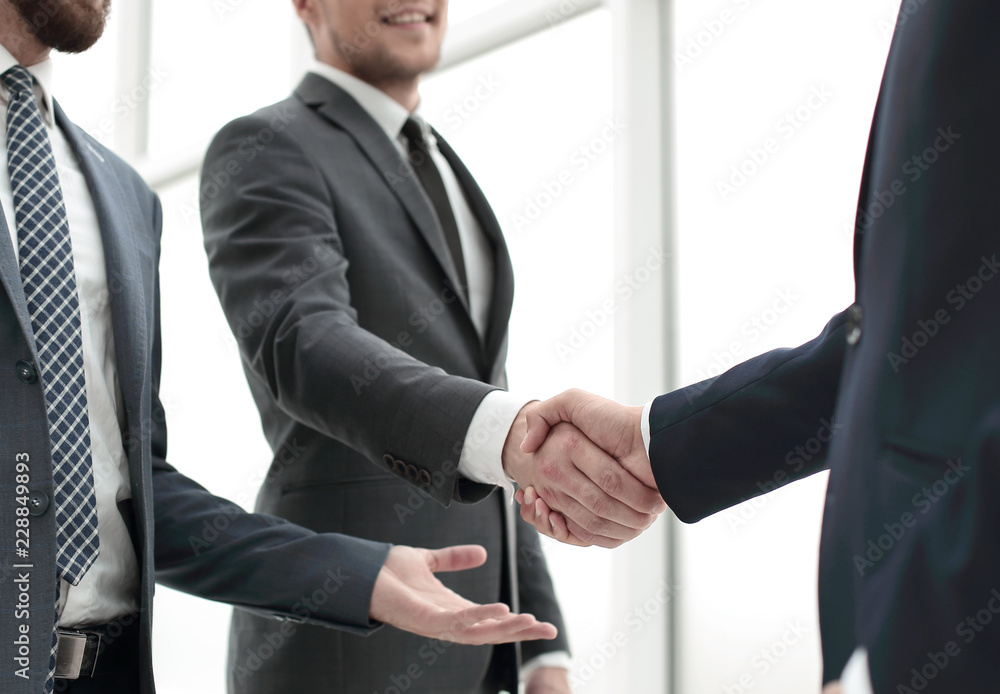 business people shaking hands while standing in the office
