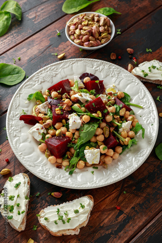 Healthy Beet Salad with chickpeas, pistachios nuts, feta and melted cheese toast on rustic wooden background