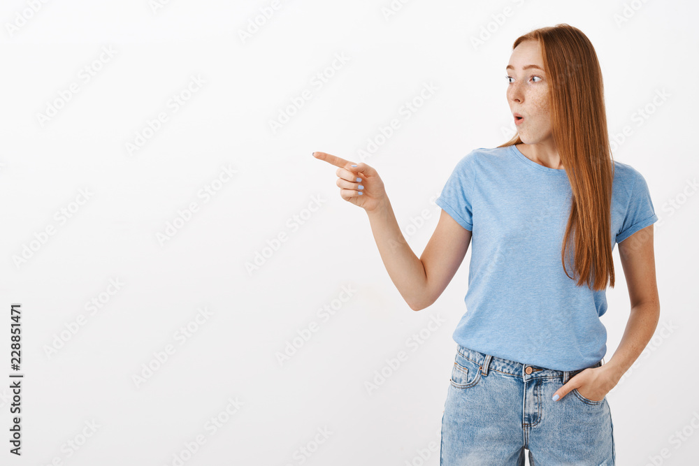 Wow it is incredible. Portrait of amazed and impressed speechless cute redhead woman in blue t-shirt folding lips whistling from interest and surprise looking and pointing left astonished Wow it is incredible. Portrait of amazed and impressed speechless cute redhead woman in blue t-shirt folding lips whistling from interest and surprise looking and pointing left astonished