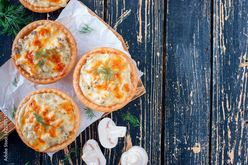 Homemade savory autumn tarts with fresh seasonal mushrooms in a crisp pastry base on gray background