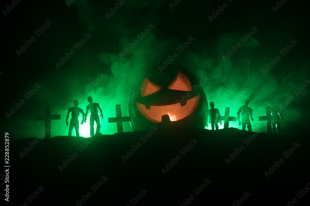 Scary view of zombies at cemetery dead tree, moon, church and spooky cloudy sky with fog, Horror Halloween concept with glowing pumpkin.