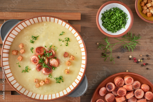 Photography Flat lay of homemade cream of potato soup with croutons, fried vienna sausages a