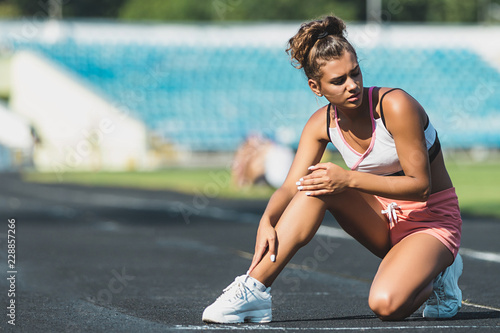 Sport woman getting hurt on legs on stadium