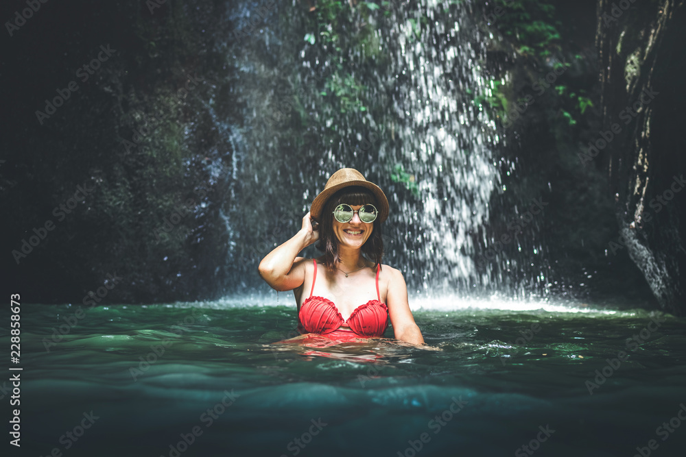 Fototapeta premium Young woman tourist in the deep jungle with waterfall. Real adventure concept. Bali island.