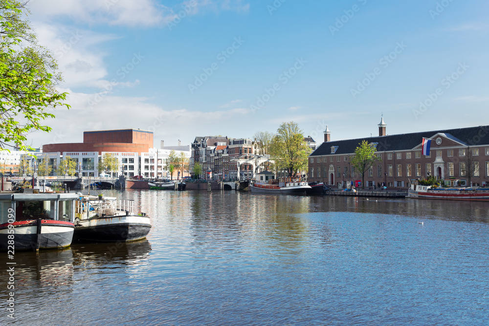 embankments of Amstel canal with traditional boats and houses in Amsterdam, Holand