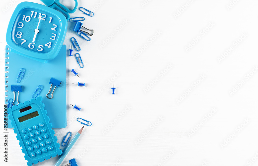 Back to school or college concept, top view flat lay of blue school supplies (clock, notebook, pencil, pen, calculator, clips and pins) on white table background with copy space Back to school or college concept, top view flat lay of blue school supplies (clock, notebook, pencil, pen, calculator, clips and pins) on white table background with copy space