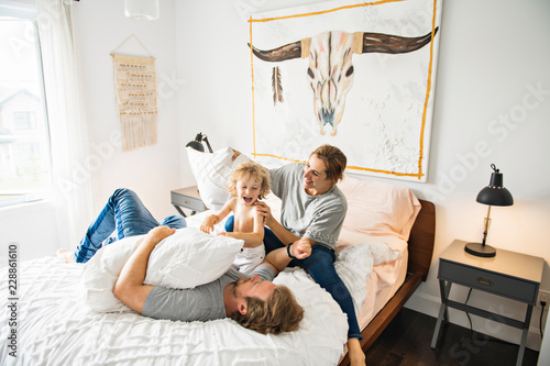 Family with child having fun on bed with pillow fight