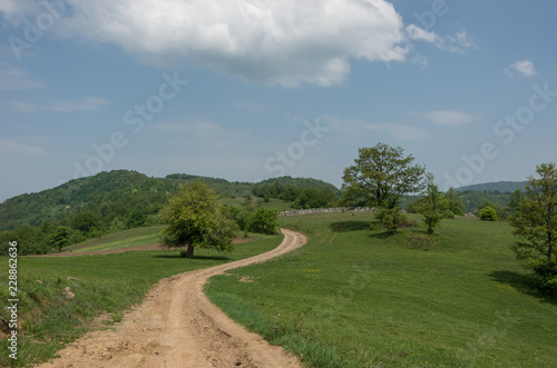 Landscape with hills, meadows and dirt road on Radan mountain massif, near rock formation Djavolja Varos (Devil's town) in the South of Serbia.