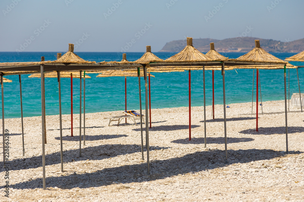 Umbrellas on the Borsh Beach in Albania. Stony beach on the Adriatic Sea. Umbrellas on the Borsh Beach in Albania. Stony beach on the Adriatic Sea.