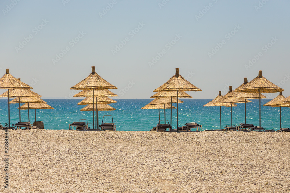 Fototapeta premium Umbrellas on the Borsh Beach in Albania. Stony beach on the Adriatic Sea.