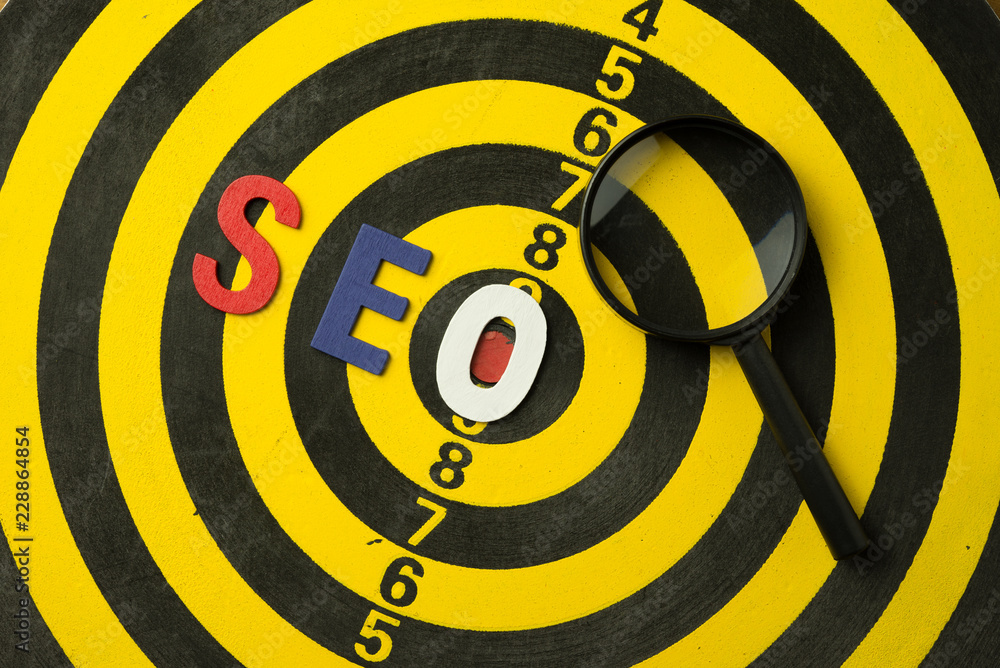 SEO Search Engine Optimization multi color logo alphabets ranking concept on dartboard background with magnifying glass, SEO is one of online marketing business strategy to promote website. SEO Search Engine Optimization multi color logo alphabets ranking concept on dartboard background with magnifying glass, SEO is one of online marketing business strategy to promote website.