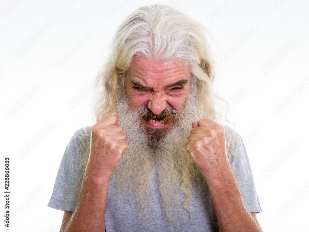 Close up of angry senior bearded man looking furious while raisi Close up of angry senior bearded man looking furious while raisi