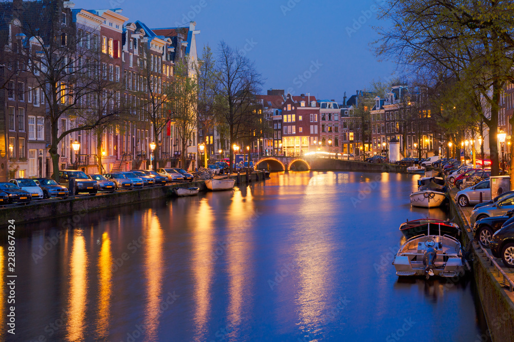 Houses and bridges over canal illuminated at night, Amsterdam, Netherlands