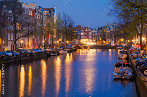 Houses and bridges over canal illuminated at night, Amsterdam, Netherlands
