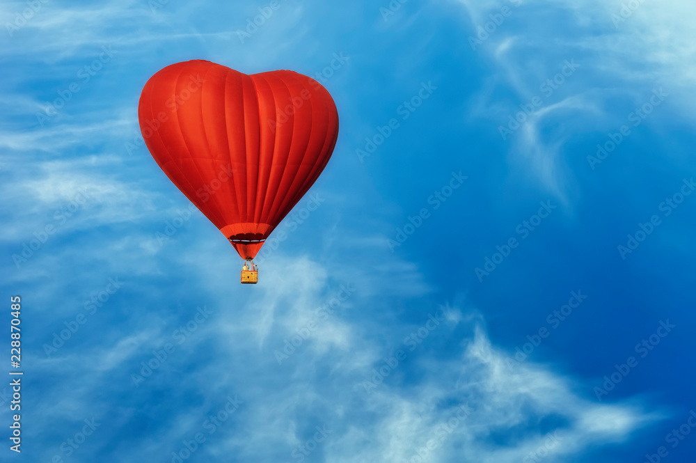 Naklejka Bright red hot air balloon in the shape of heart against blue sky