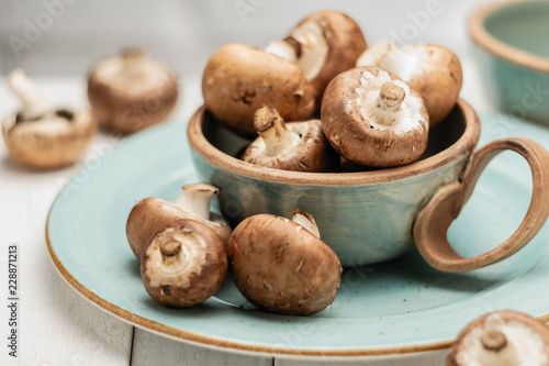 royal champignons in ceramic tableware on wooden white background