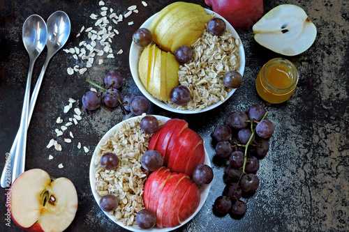 Oatmeal with honey and fruit. Porridge in bowls with apple, pear, honey and grapes. Healthy and beautiful breakfast. The concept of dietary nutrition. Superfoods