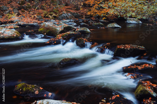 Blurry motion of a blue mountain river with autumn color tones leaves. Bode Gorge (Bodetal), National Park Harz Mountains, Thale, Saxony-Anhalt in Germany