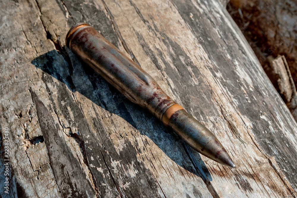 Combat large-caliber cartridge with a bullet on a wooden background. Combat large-caliber cartridge with a bullet on a wooden background.