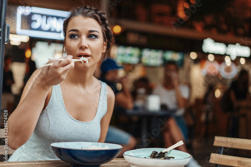 Beautiful woman eating chicken with rice in street cafe of chinese food.
