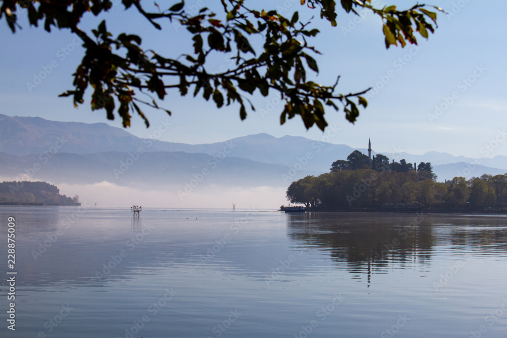 Lake Pamvotis on a misty morning in Ioannina, Greece, with Aslan Pasha mosque in the background