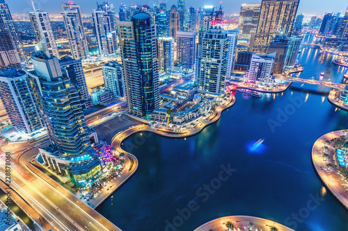 Scenic nighttime skyline of big modern city with illuminated skyscrapers. Aerial view of Dubai Marina, UAE. Multicolored travel background.