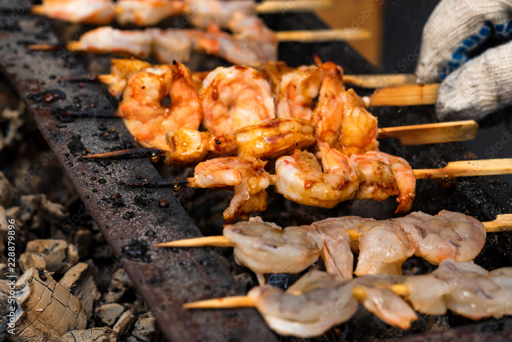 Grilled fried seafood on skewers on metal grid