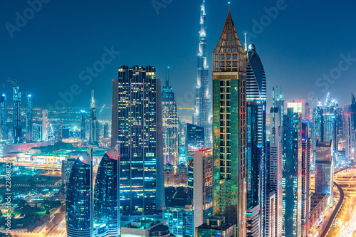 Spectacular urban skyline with colourful city illuminations. Aerial view on highways and skyscrapers of Dubai, United Arab Emirates.