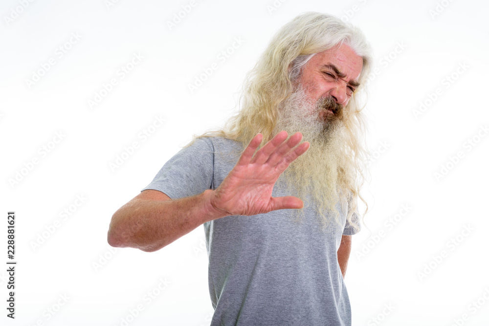 Studio shot of senior bearded man looking disgusted while showin Studio shot of senior bearded man looking disgusted while showin