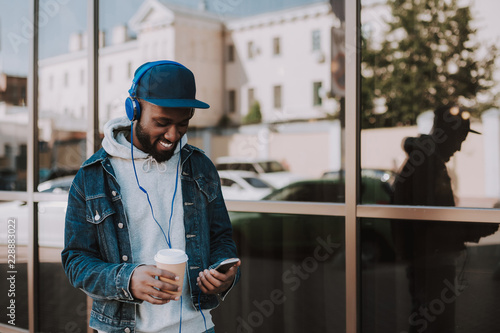 Cheerful handsome young afro american man using his phone while enjoying best songs