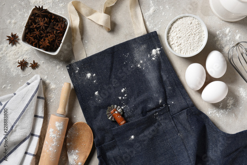 Slika na platnu A denim apron with eggs, flour and equipment for making holiday cookies and dess