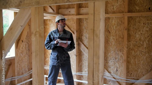 Architect or builder check plans in a half built timber frame house. Engineer on the construction of a frame wooden house. 4k