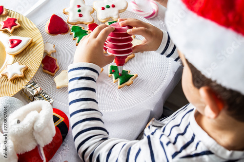 Little kid decorating Christmas biscuits at Christmas day