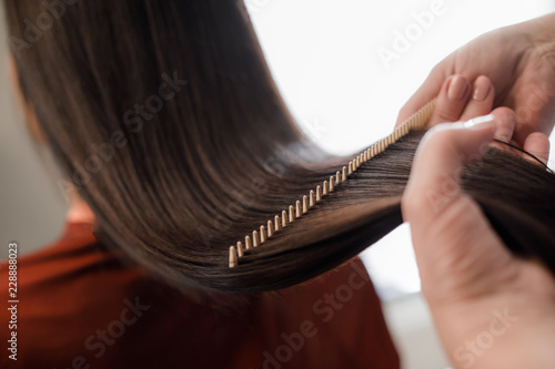 Close up of hairstyle master hands combing long hair with special hairbrush