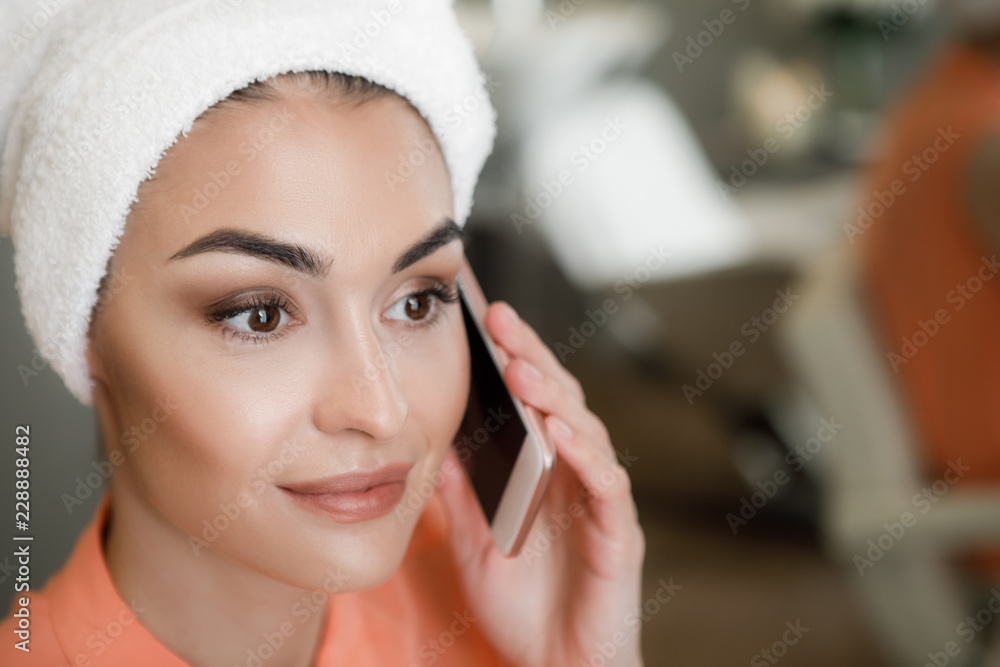 Close up portrait of pretty lady with excellent makeup talking by phone in beauty salon. Copy space on right side Close up portrait of pretty lady with excellent makeup talking by phone in beauty salon. Copy space on right side