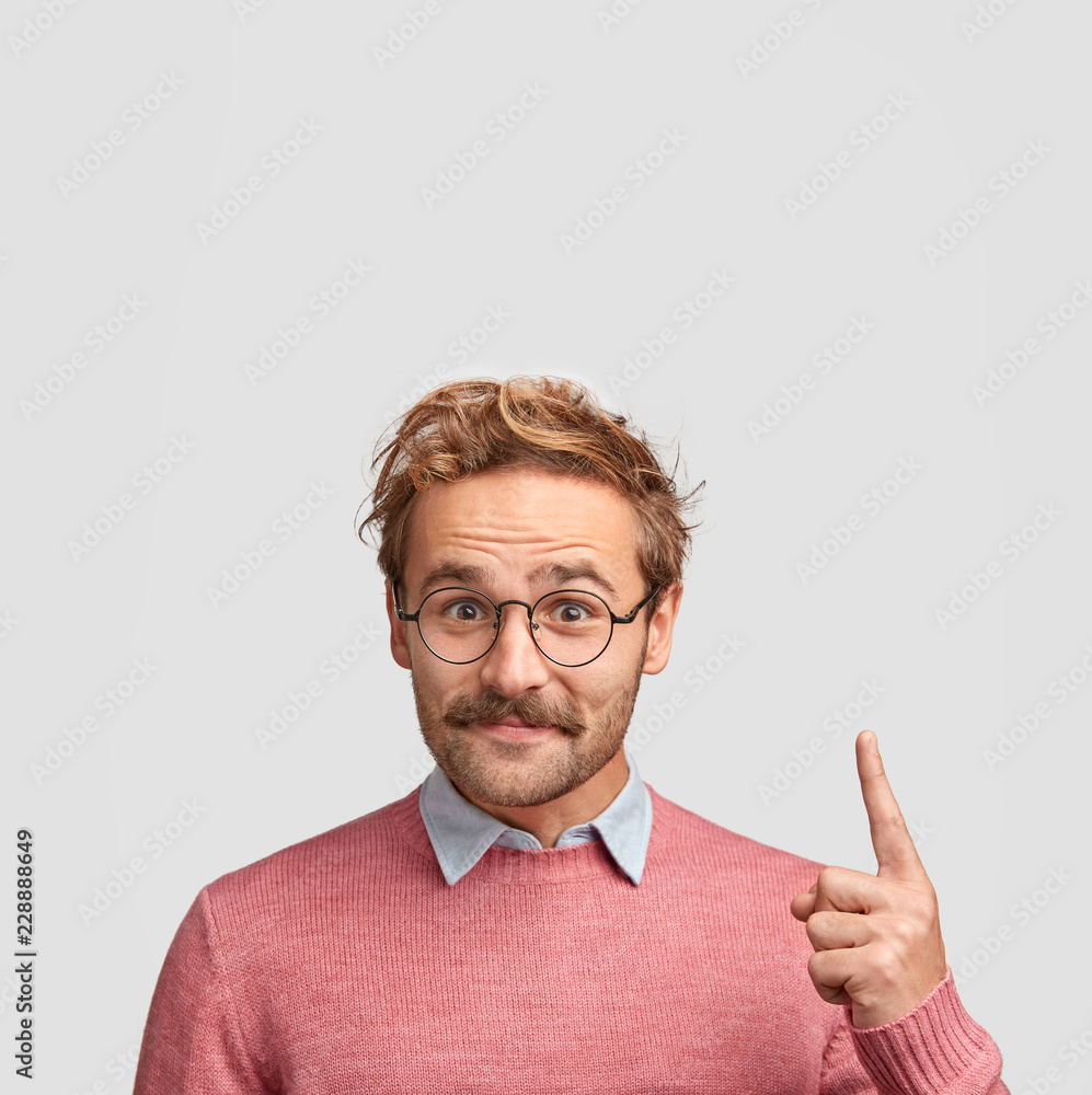 © WHstudio Leushin N - Stylish man with curly hair, mustache, wears pink sweater, points with index finger upwards, shows blank space for your advertising content, isolated over white background. People and advertisement © WHstudio Leushin N - Stylish man with curly hair, mustache, wears pink sweater, points with index finger upwards, shows blank space for your advertising content, isolated over white background. People and advertisement