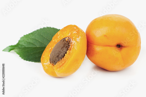 ripe juicy yellow apricots with leaves on a white table