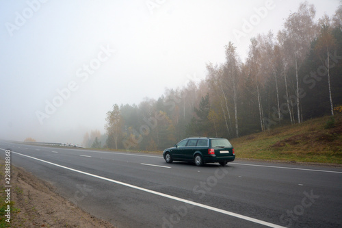 Car on the road in the fog. Autumn landscape. © lastfurianec