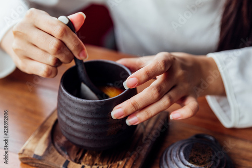 Japanese Caramel Pudding served in black ceramic cup that scoop soft pudding by woman hand.