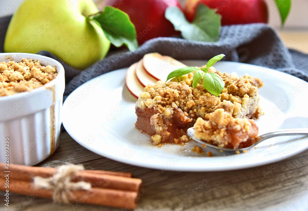 Apple crumble on with dish with spoon and fresh green and red apple with cinnamon stick on wooden floor. Easy and Basic dessert menu. Apple crumble on with dish with spoon and fresh green and red apple with cinnamon stick on wooden floor. Easy and Basic dessert menu.