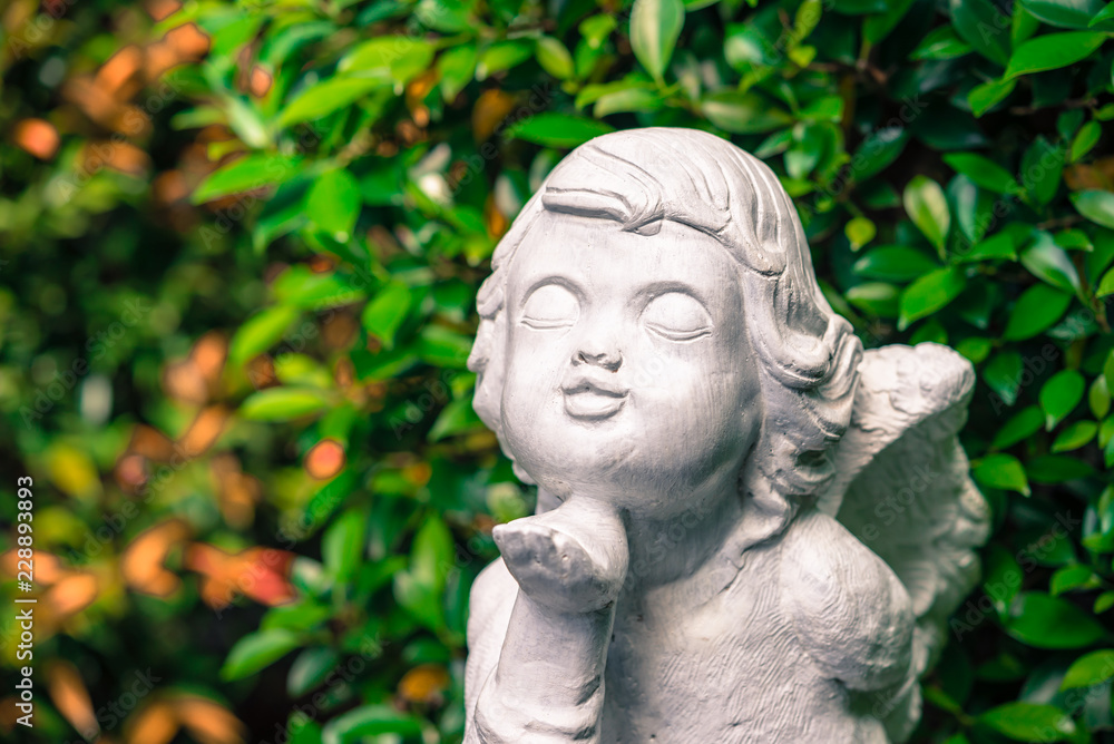 Vintage style cute cupid statue in green garden