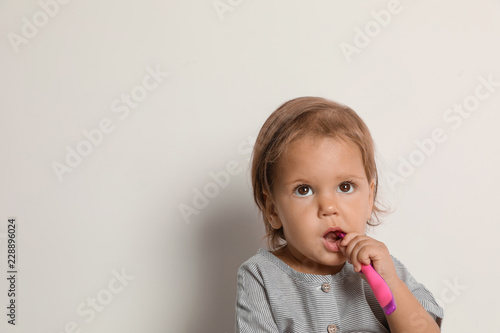 Cute little girl with toothbrush and space for text on white background